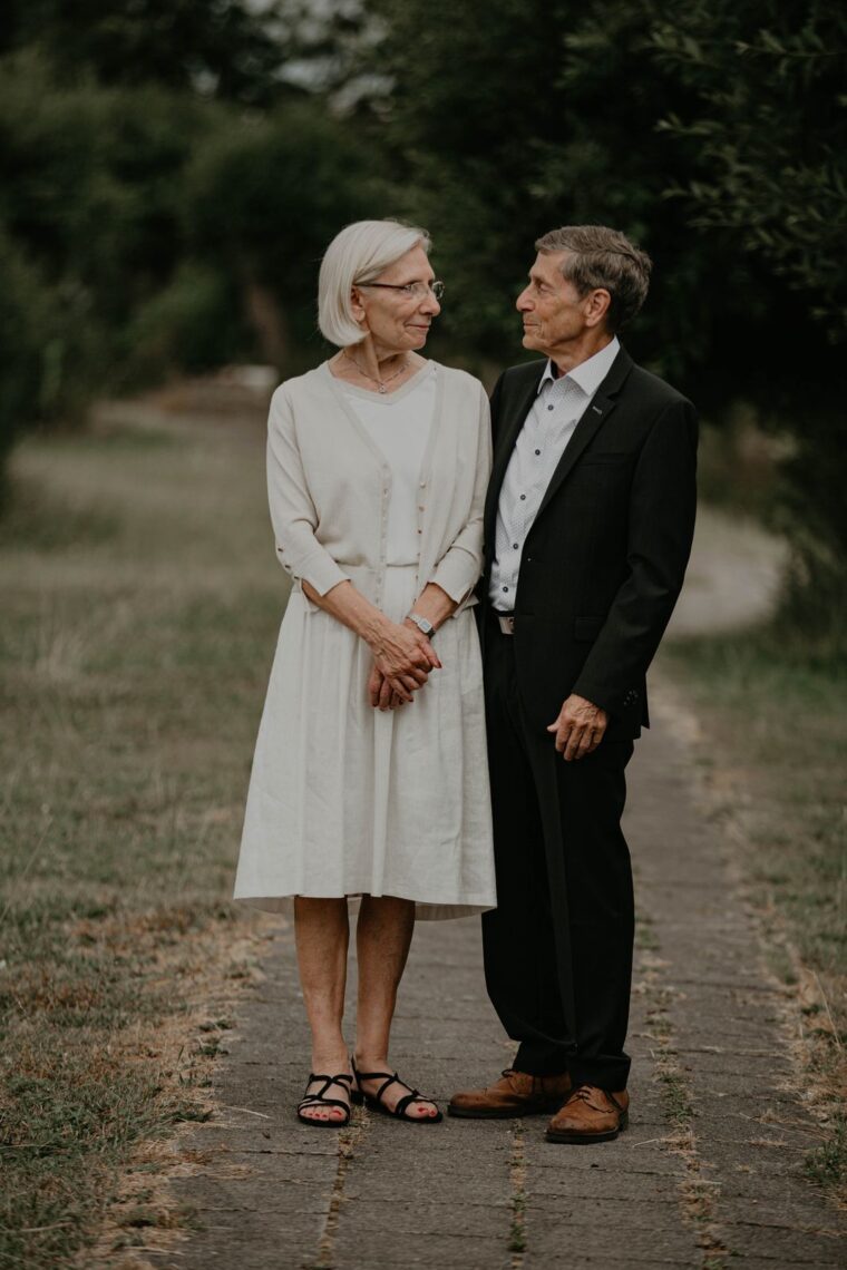 Senior couple in elegant attire sharing a tender moment outdoors.